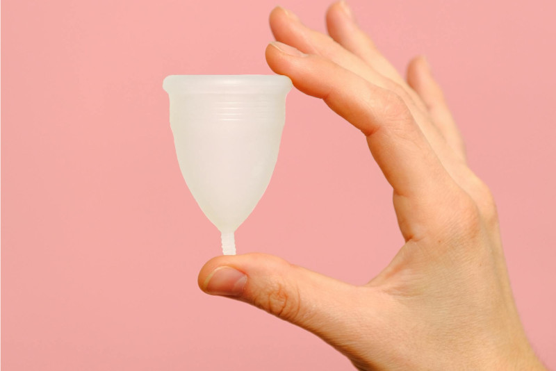 main d'une femme tenant une cup menstruelle en silicone